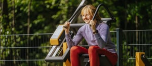 En kvinna tränar mage på ett utegym – styrketräning med justerbara vikter i stålgym.