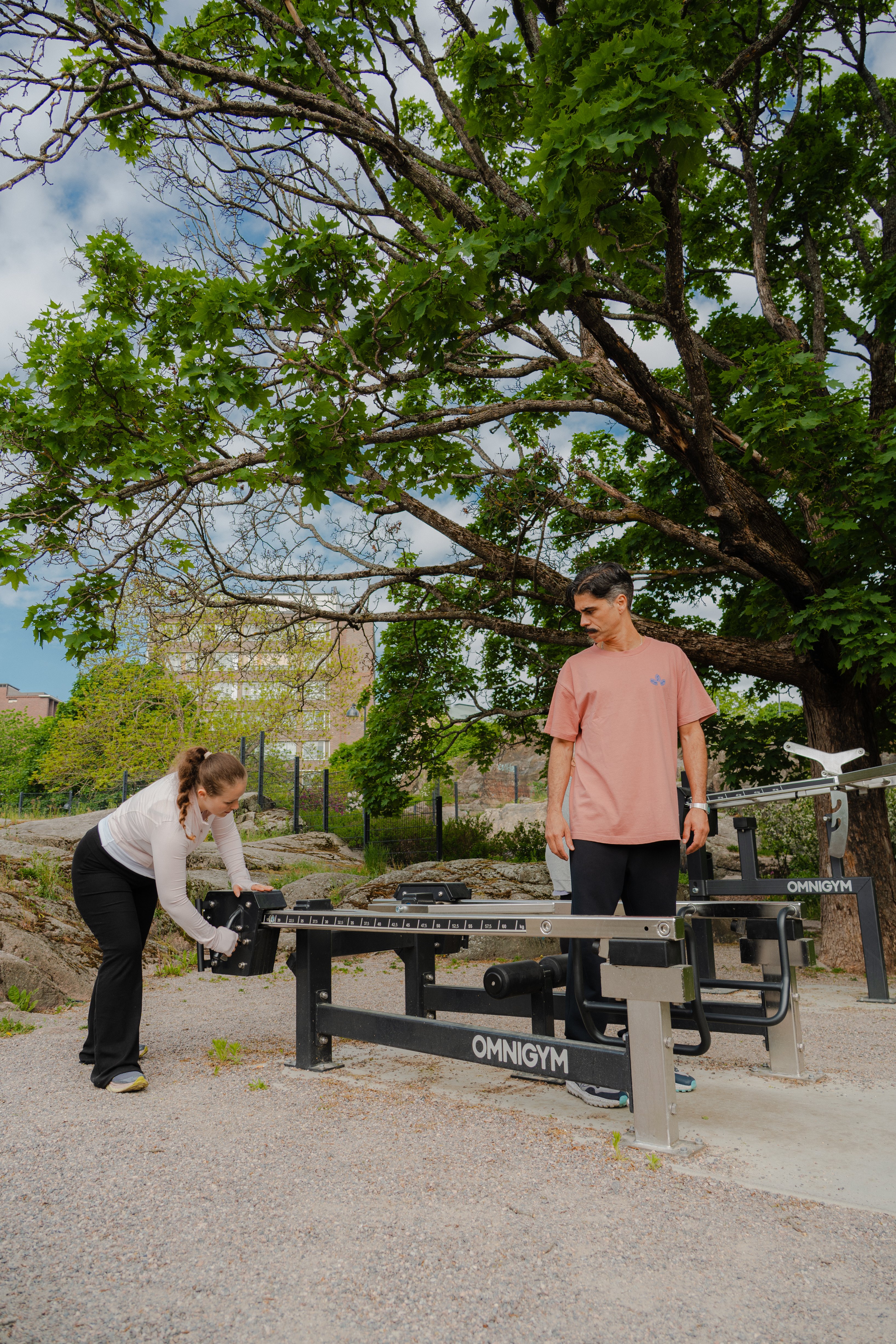 Two people adjusting Multi lift at an outdoor gym