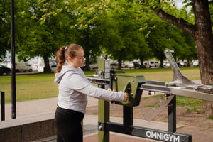 a woman adjusting a weight unit at an outdoor gym