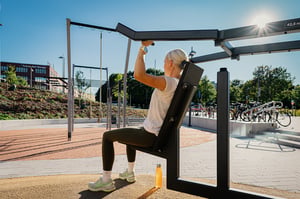 A woman working out shoulders at an outdoor gym