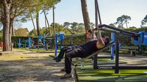 Homme essayant le développé couché Omnigym à la salle de sport extérieure Seignosse Naturéo Eco-Resort