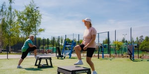 Women stretching and walking up and down on plyo boxes in an outdoor gym.