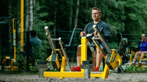 Senior man smiling while performing a seated row exercise at an Omnigym outdoor gym, showcasing strength training in a sunny, open-air environment.