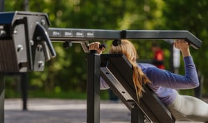 kvinna tränar på ett utegym med justbara vikter