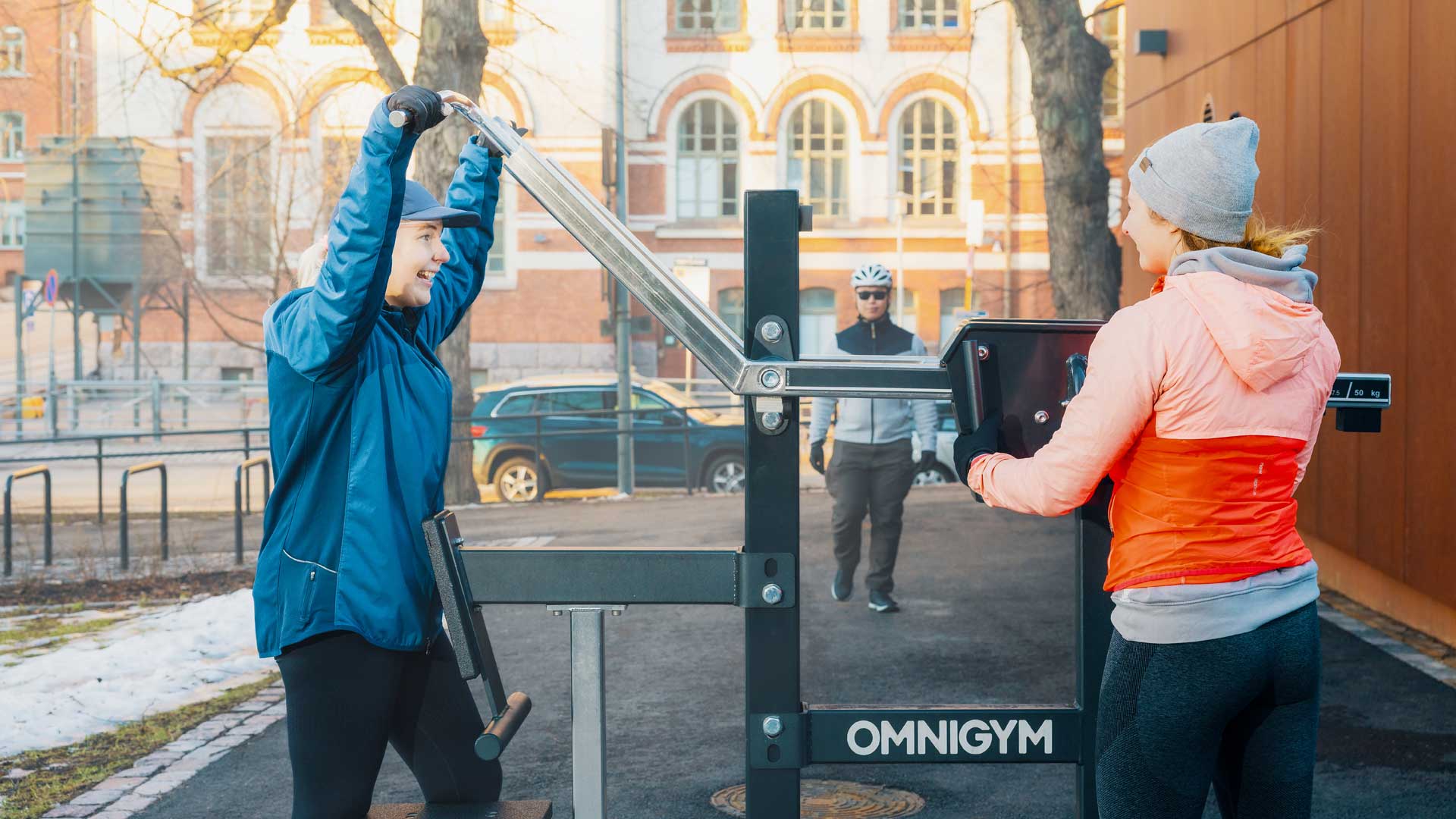 Équipements de fitness en plein air Omnigym avec deux femmes utilisant une machine de tirage vertical en hiver près de Johanneksenkirkko, Ullanlinna, Helsinki Équipements de fitness en plein air Omnigym avec deux femmes utilisant une machine de tirage vertical en hiver près de Johanneksenkirkko, Ullanlinna, Helsinki