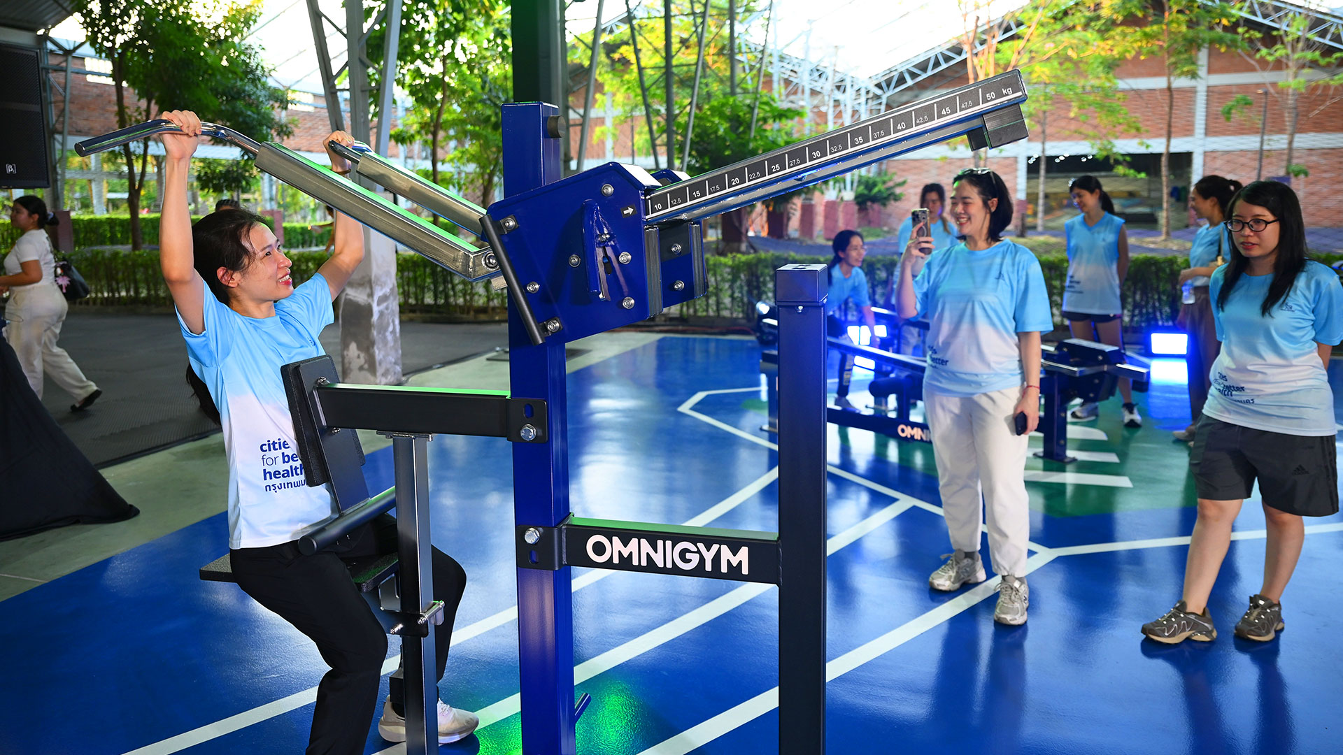 A group of women trying the Omnigym lat pulldown at the public outdoor gym in Benchakitti Forest Park.